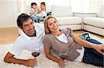 Affectionate lovers drinking wine lying on the floor in the living room