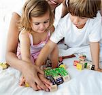 Close-up of brother and sister playing with cube toys on the bed