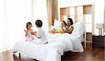 Parents having breakfast and children playing on the bed