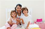 Attractive mother and her children playing with letters blocks in the bedroom