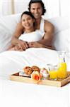 Happy couple having breakfast on the bed
