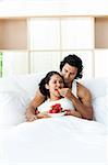 Young lovers eating strawberries lying on the bed