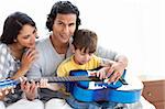 Cute little boy playing guitar with his parents at home