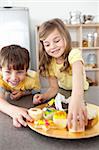 Sister and brother eating cookies in the kitchen