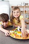 Brother and sister eating cookies in the kitchen