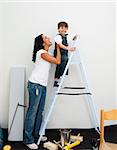 Adorable little boy climbing a ladder while renovating a room