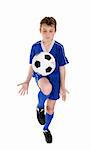 A boy using a soccer ball skills practice.  Ball has some motion.  White background.