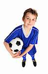 A smiling boy in soccer uniform ready for a game of soccer.  White background.