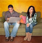 Hispanic Couple on Green Couch with Computer Woman is Bored