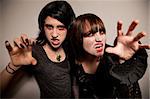 Two young vampire girls with sharp fangs reaching towards the camera