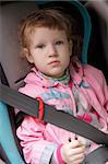 Cute exhausted little girl in a baby car seat.