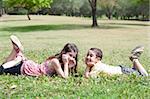Cute children lie down on green grass and looking eachother in the park, outdoor