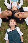 Lively family lying in a circle on the grass in a park