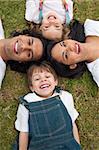 Adorable little boy lying in a circle with his family in a park