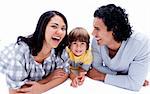 Laughing parents with their son lying on the floor against a white background