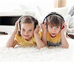 Siblings listening music lying on floor in the living room