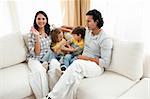 Merry family having fun in the living room sitting on sofa