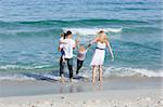 Jolly family walking on the sand at the beach