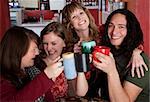 Four friends with mugs toasting at a cafe