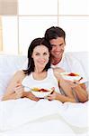 Affectionate couple having breakfast lying in the bed