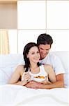 Smiling couple having breakfast lying in the bed