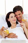 Intimate couple drinking orange juice lying in the bed