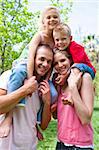 Happy parents giving their children piggy-back ride in a park