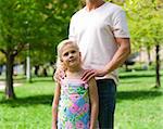 Cute little girl with her father in a park looking at the camera