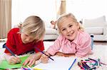 Cheerful children drawing lying on the floor in the living-room