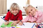 Smiling children drawing lying on the floor in the living-room