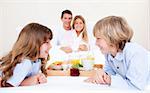 Cheerful family having breakfast sitting on bed at home