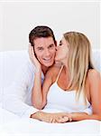 Intimate woman kissing her husband sitting on bed at home