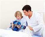 Adorable little boy playing guitar with his father in the bedroom