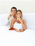 Loving couple drinking Champagne with strawberries lying on their bed