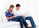 Young couple working at home sitting on sofa