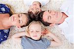 Relaxed family lying in circle on the wall-to-wall carpet at home