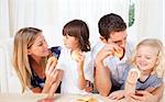 Joyful family eating breakfast in the kitchen at home