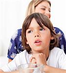 Captivated child watching television with his mother in the living room