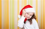 little girl wearing santa claus red hat looking at camera