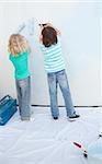 Siblings painting a wall in their new house