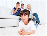 Smiling little boy listening music lying on floor in the living room