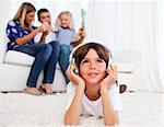 Pensive little boy listening music lying on floor in the living room