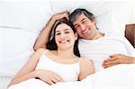 Smiling couple hugging lying in their bed at home