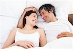 Enamored couple hugging lying in their bed at home