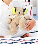 Close-up of a teddy bear with headphones on on a bed