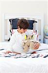 Cute little boy playing with a teddy bear in his bedroom