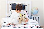 Adorable little boy playing with a teddy bear in his bedroom