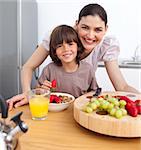 Cheerful mother and her child having breakfast in the kitchen