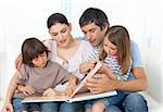 Attentive parents reading with their children on the sofa