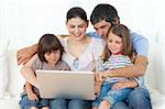 Jolly family using a laptop on the sofa at home